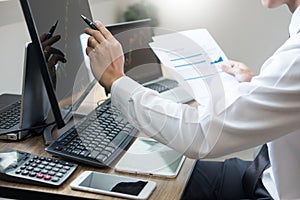 Stock exchange trader Analyzing Graphs chart or data On Multiple Screens in office
