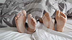 Stock footage of a happy family's feet under the blanket. Perfect for representing family time, closeness, and intimacy.