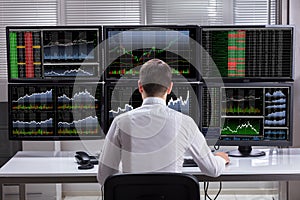 Stock Market Broker Analyzing Graphs On Computer Screens