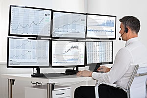 Stock Market Broker Looking At Graphs On Multiple Screens photo