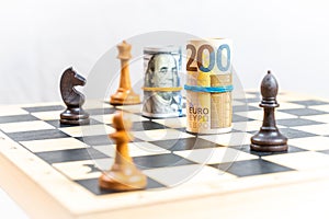 Stock market concept, chess game with dollar and euro rolled bills along selected white and black chess figures.