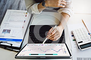 stock market ideas, investments, risk management Woman holding pen pointing to tablet studying stock market from her
