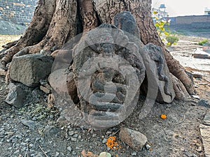 Stock photo of Ancient ruined archeological sculpture depicting Indian god or snake idol carved on granite stone kept near the