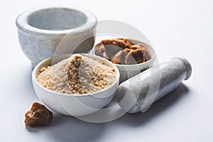 Stock Photo of Asafoetida powder / Hing or Heeng with cake and mortar