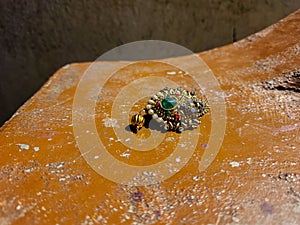 Stock photo of beautiful golden color saree pin or brooch decorated with pearl, red, white stone, green color stone in the middle