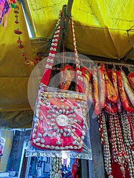 Stock photo of beautiful and traditional handmade red color bag decorated with white color cowry shell,hanging outside of the shop