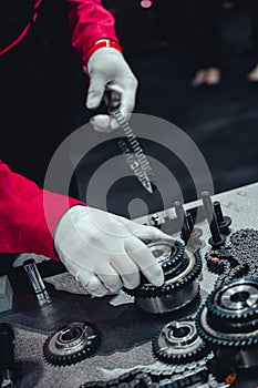 Mechanic wearing white gloves building engine picking up a gear from working table