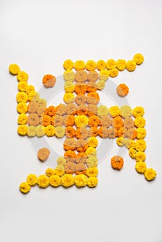 Stock photo of hindu auspicious symbol called Swastika made using marigold flower or zendu or genda phool, Flower rangoli in the s photo