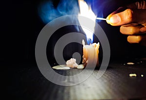 Stock photo of a human hand holding lighted matchsticks with yellow and blue color flame for lighting up the white color small