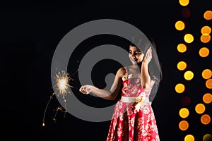 Stock photo of indian little girl holding fulzadi or sparkle or fire cracker on diwali night