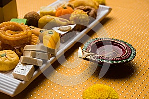 Indian sweets or Mithai for diwali festival with oil lamp or diya and gift box