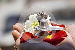 Stock photo of a man holding and worshiping silver shivlinga which is icon of lord shiva on the occasion of mahashivratri , photo