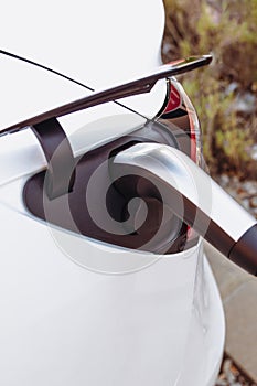 Stock photo of a plug charging a modern electric car or EV car in power station. Sustainable mobility and Eco-friendly alternative