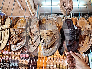 Stock photo of popular and traditional kolhapuri chappal hanging in the display for sale in the local shop.It is handmade leather