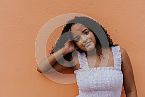 Stock photo of a portrait of a young woman against the wall. She has confident attitude and looking at camera. She is wearing