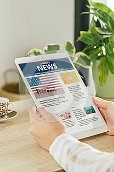 Stock photo of a woman reading news online on her tablet. Concept of online information and reading newspapers on the internet.