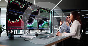 Stock trader analyzing market data on multiple monitors with financial graphs