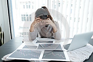 A stockbroker girl has stress, headaches, analyzes, and calculates the stock market that is falling