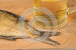 Stockfish and glass of beer on a wooden board