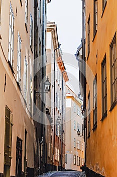 Stockholm narrow street. Orange, yellow houses and street lights. View from below of a cozy narrow medieval street