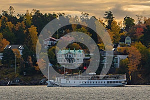 Stockholm, Sweden. Boat passing by houses in early morning in autumn. Colorful landscape