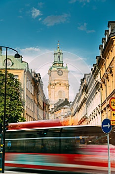 Stockholm, Sweden. Red Bus In Motion Blur Rides Near Old Town With Tower Of Storkyrkan - The Great Church Or Church Of