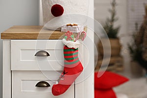 Stocking with presents hanging on drawer in children`s room, space for text. Saint Nicholas Day tradition