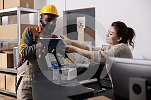 Stockroom manager putting worker to sign goods checklist