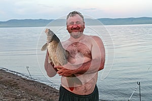 Stocky man with big carp. Khakassia