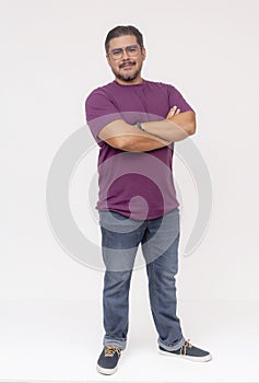 A stocky middle aged man wearing glasses, hands on hips and one foot up. Full body photo, wearing purple waffle shirt and jeans,