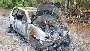 Stolen abandoned and burned out car in road forest