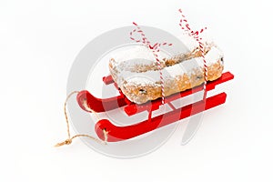Stollen, German Christstollen, on Red Wooden Sledge isolated on White