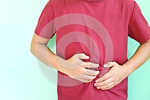 Stomach and abdominal pain concept. Young asian man holding his stomach area.