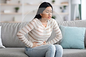 Stomach Ache. Sick Asian Woman Suffering From Acute Abdominal Pain At Home