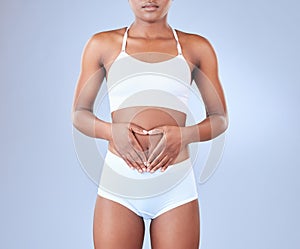 Stomach, heart hands and woman with underwear, wellness and healthy gut on blue studio background. Person, mockup space