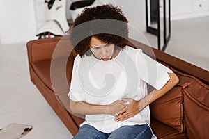 Stomach pain. Sick african american girl hold abdomen because it hurts. Pancreatitis disease of pancreas becomes