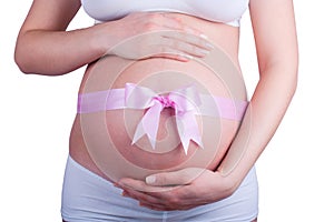 Stomach of pregnant woman with pink ribbon