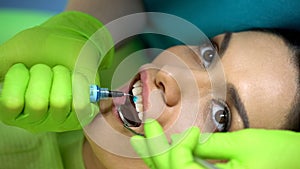 Stomatologist applying blue gel on tooth, cosmetic dentistry, aesthetics