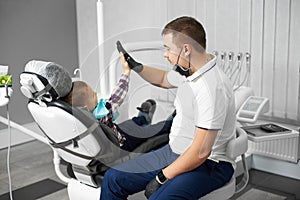 Stomatologist and cute kid after treating teeth giving high-five