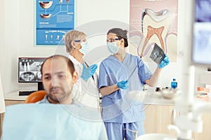 Stomatologist doctor and orthodontist assistant examining teeth radiography