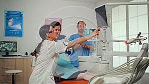 Stomatologist pointing on digital screen explaining x-ray to mother