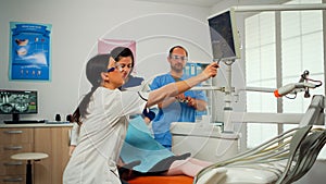 Stomatologist pointing on digital screen explaining x-ray to mother