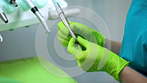 Stomatologist putting drill into handpiece, preparing for procedure, dentistry photo