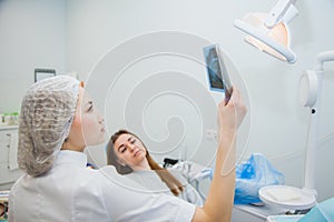 Stomatologist showing dental x-ray image to patient at clinic office.