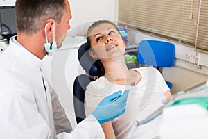 Stomatologist in uniform is taking visional inspection of an adult patient on the chair