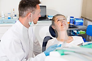 Stomatologist in uniform is taking visional inspection of a girl on the chair