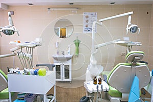 Stomatology interior of small dental clinic with professional chair in green colors. Dentistry, medicine, medical equipment and