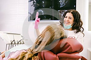 Stomotologist woman happy smiling at her work and showing two fingers up while working with a patient in a clinic. photo