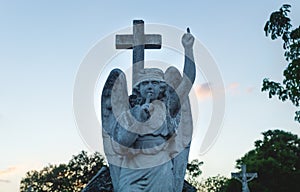 Stone angel statue with a silence sign and pointing up to heaven at the cemetery `Cementerio General` in Merida, Yucatan, Mexico