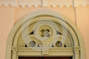 Stone arch above decorative wood gate. Ornamental carved classic geometric motives. stucco exterior wall elevation.